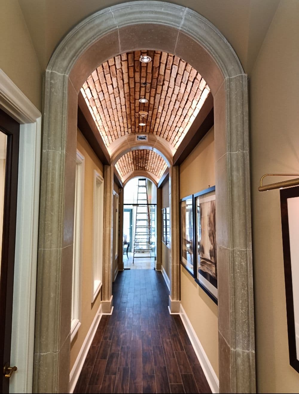 Elegant hallway with arched ceiling, brick detailing, and natural light from end.