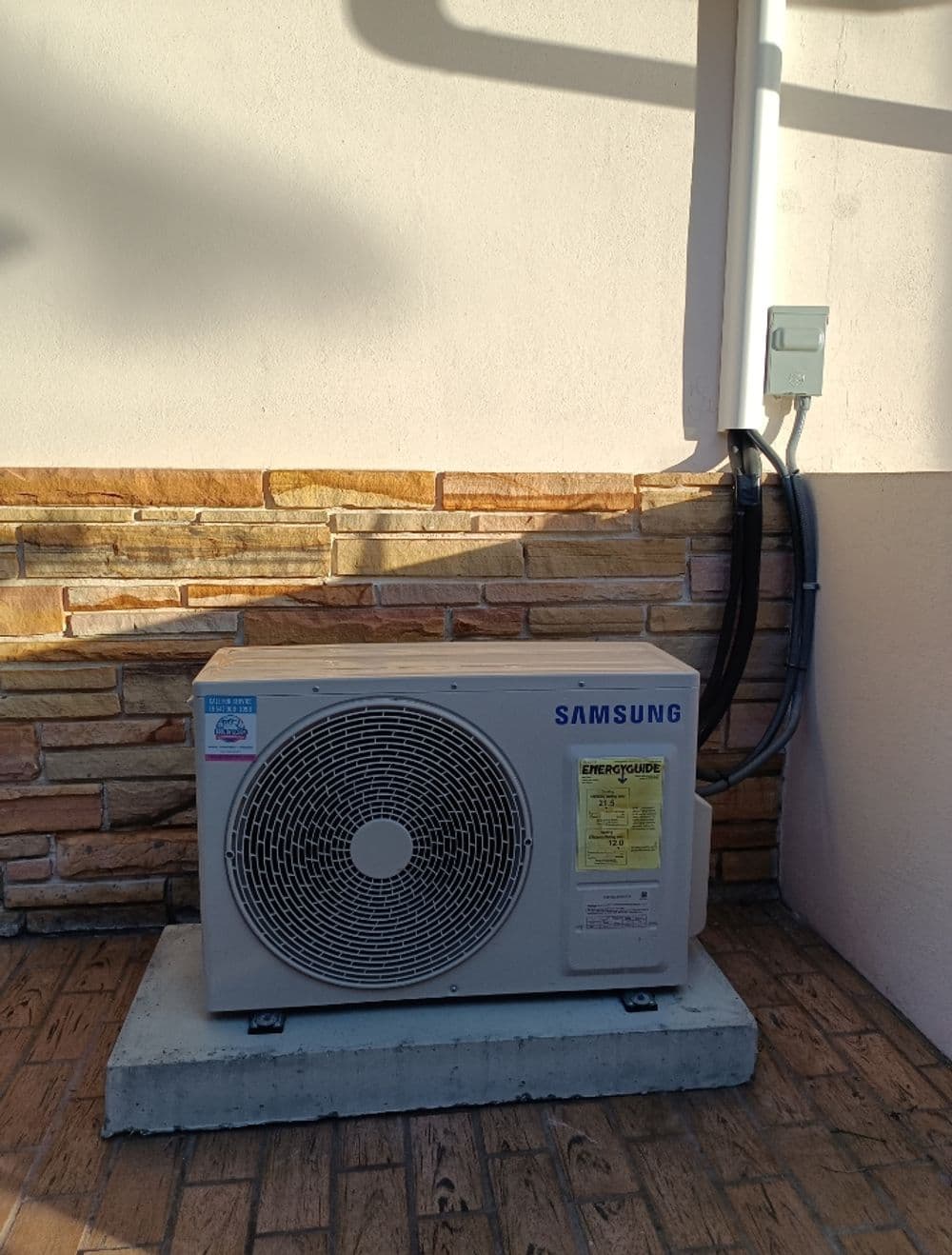 Samsung air conditioning unit installed on a concrete base outside a building.