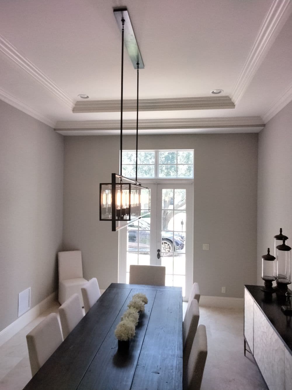 Modern dining room with a wooden table, pendant lighting, and large windows.