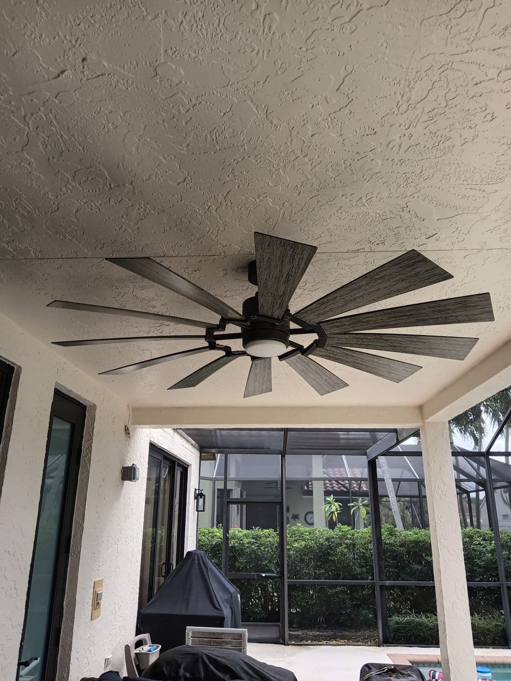 Ceiling fan with ten blades in a covered patio area, featuring a modern design.