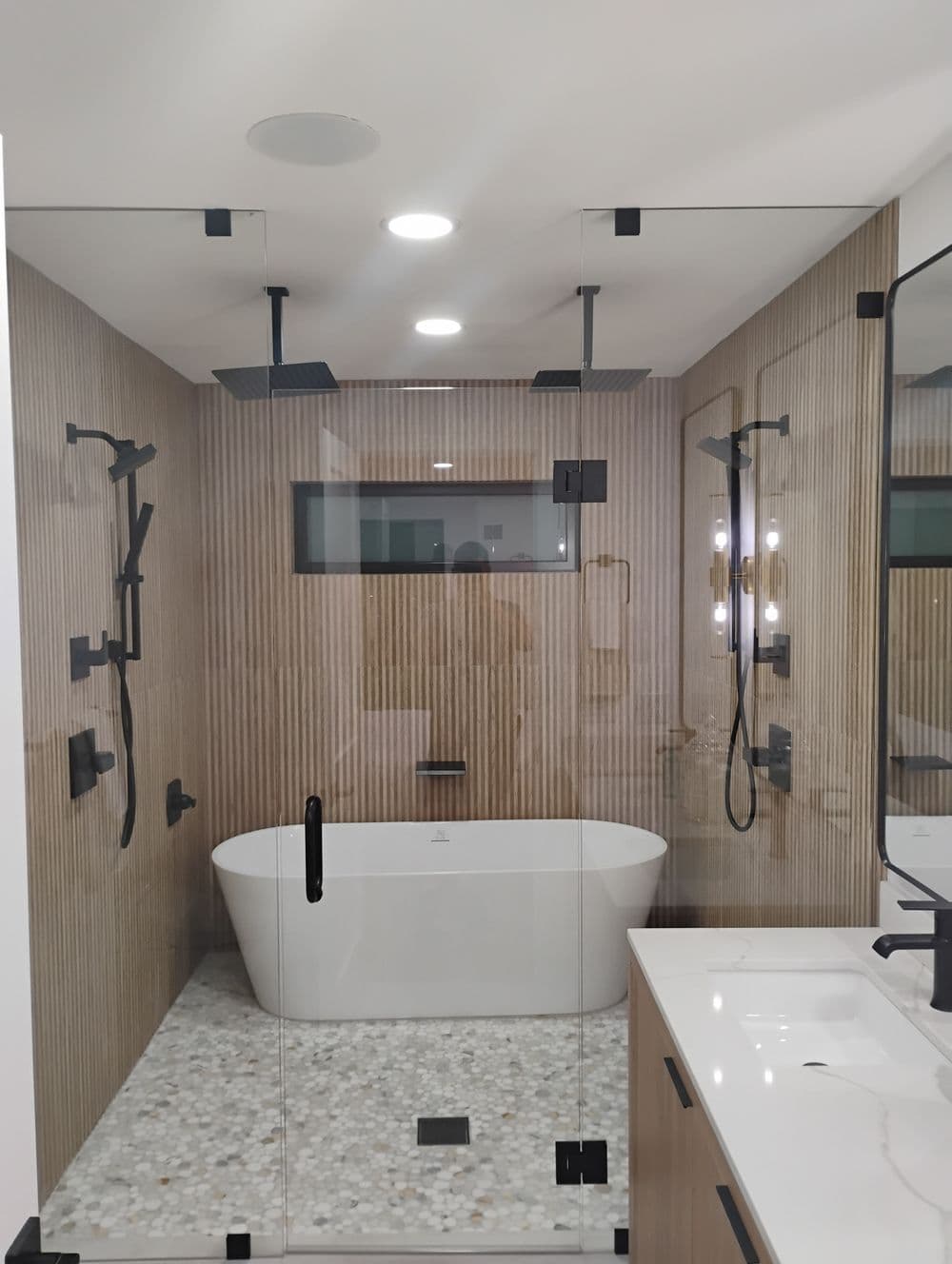 Modern bathroom featuring a freestanding tub, glass shower, and wooden paneling.